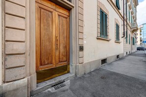 A street view with a building featuring a large wooden double door, a visible number 19, and a manhole cover on the sidewalk. - Spazio Beccaria with Private Garden - Florence (Florence)