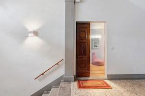 Ein Flur mit Holztür, einer Lampe, einem roten und gelben Teppich und einer hölzernen Bank.
