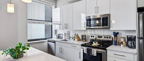 A modern kitchen with white cabinets, stainless steel appliances, and a central island with a plant.