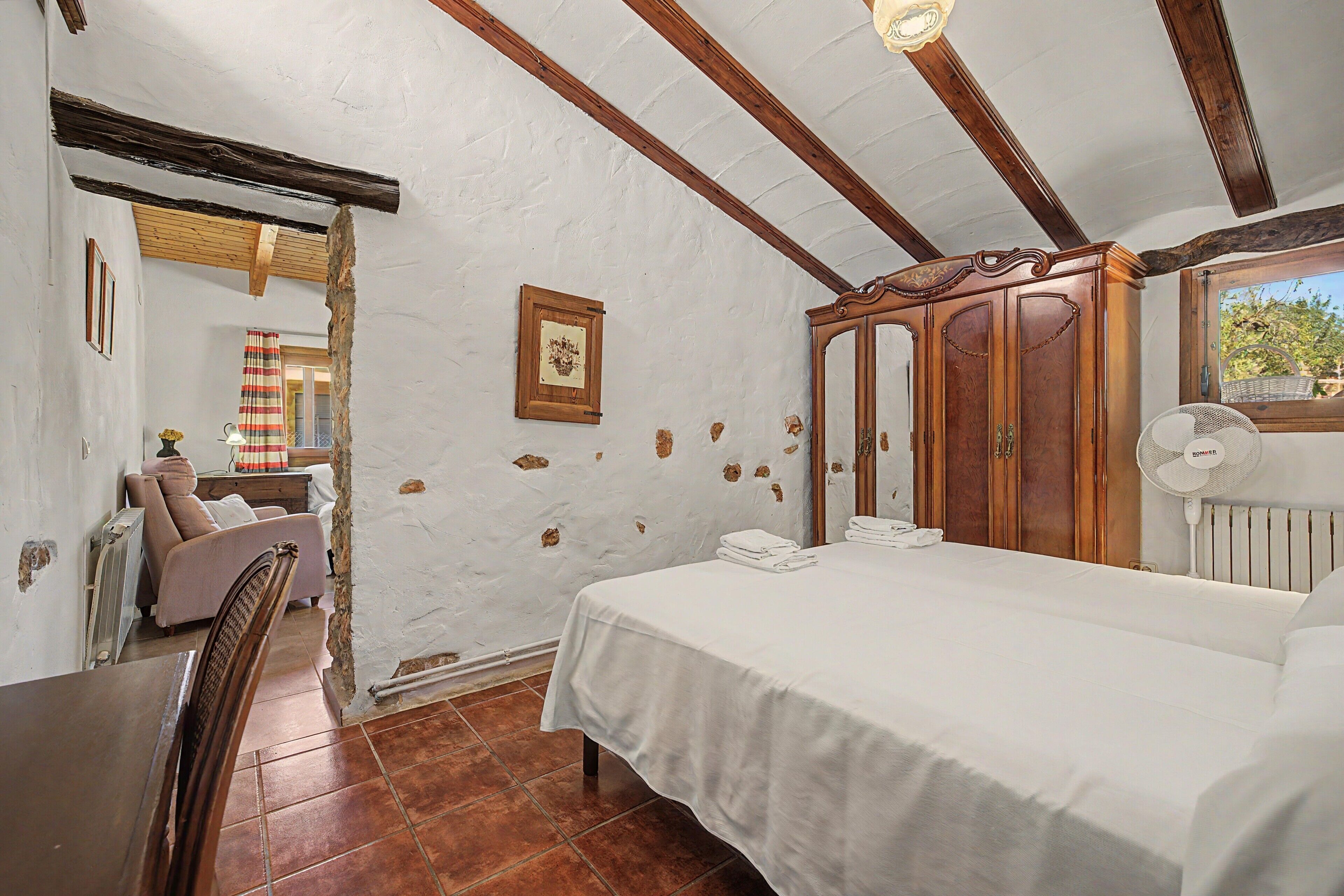 Ein Schlafzimmer mit Bett, Holzschrank, Stuhl und Heizkörper.
