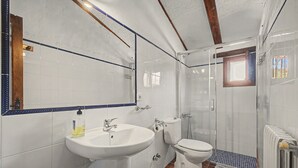 Une salle de bain avec un lavabo, des toilettes et une douche, le tout de couleur blanche.