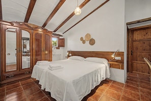 Une chambre à coucher avec un lit en bois, une table de chevet, une lampe fixée au mur et un grand miroir.