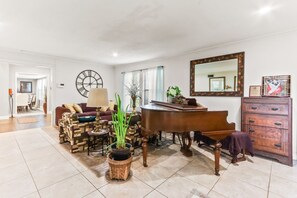 A spacious living room with a grand piano, a dining area, and a large mirror. - Buck Street - Houston (Houston)