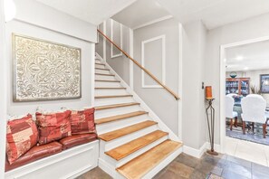 A staircase with wooden steps and a white handrail, leading to a dining area with a table and chairs. - Buck Street - Houston (Houston)