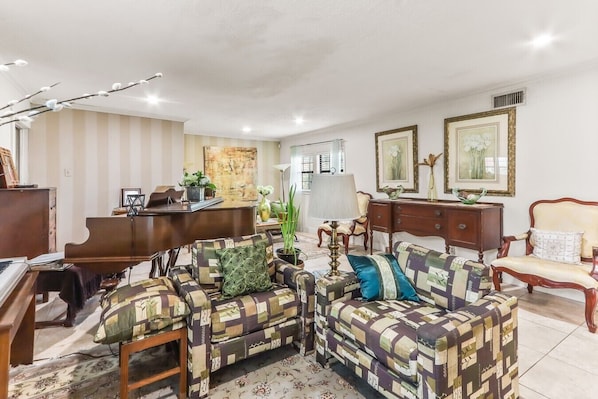A living room with a piano, a sofa set, a desk, and a lamp. - Buck Street - Houston (Houston)