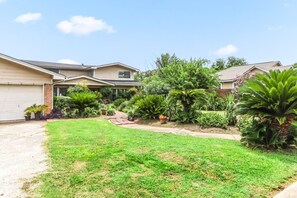 A residential property with a well-maintained lawn, a variety of potted plants, and a driveway leading to a garage. - Buck Street - Houston (Houston)