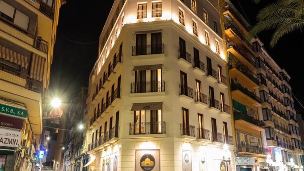 Ein mehrstöckiges Hotel mit Balkonen und beleuchteter Beschilderung.