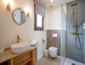 Ein modernes Badezimmer mit einer freistehenden Badewanne, einem Waschbecken mit Spiegel und einer Toilette.