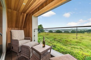 A balcony with wicker furniture, a bottle of wine, and a glass.