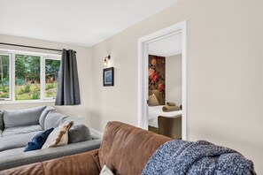 Ein modernes Wohnzimmer mit grauem Sofa, braunem Sofa und Fenster mit grauen Vorhängen.