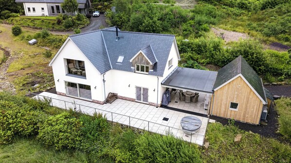 A two-story house with a covered patio and a separate wooden structure.