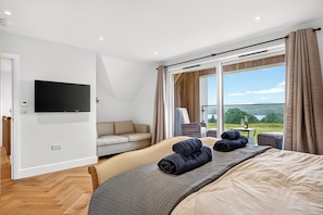 Ein modernes Hotelzimmer mit Bett, einer Couch, einem Fernseher und einem großen Fenster mit schöner Aussicht.