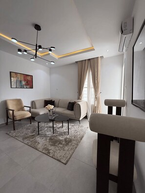 Ein modernes Wohnzimmer mit Sofa, Sesseln, Couchtisch und einer Bank.