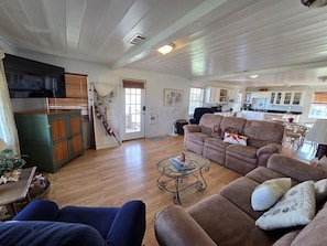 A spacious living room with a large brown sofa, a glass coffee table, and a television. - Great House with a View by the Short Jetty and Kingfisher Beach (Port O`Connor)