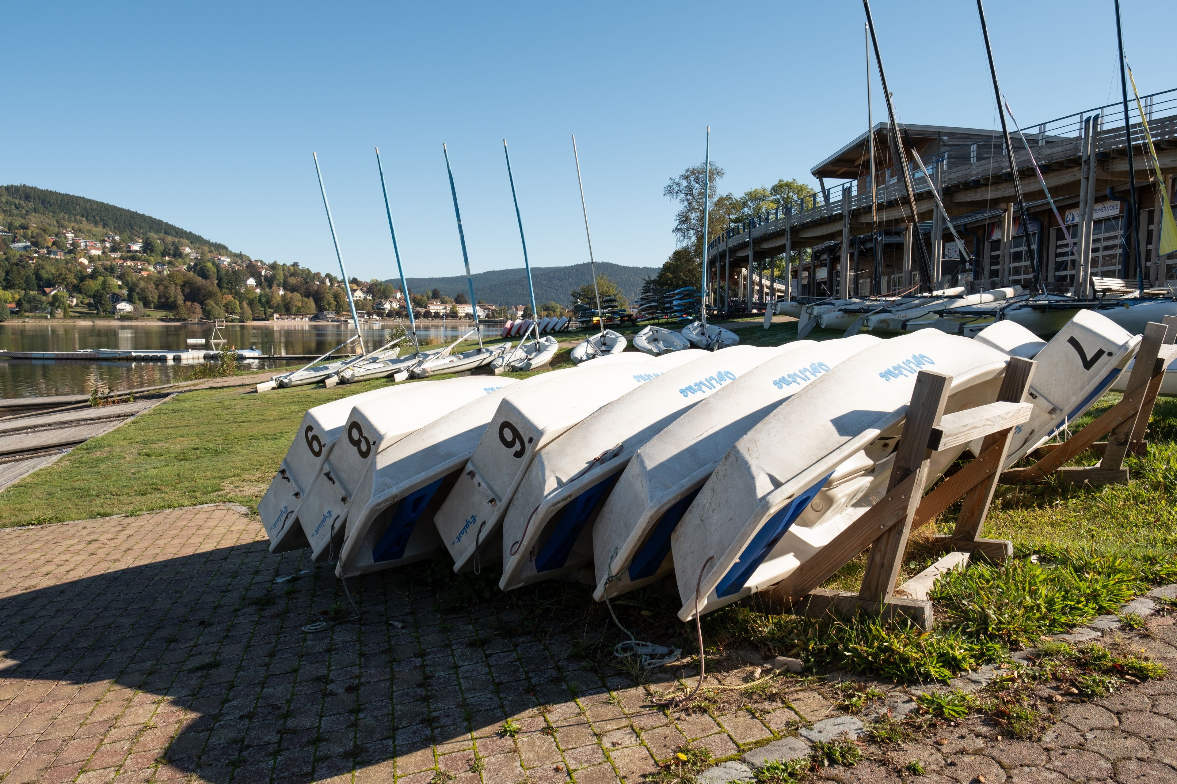 A row of numbered boats lined up on a dock with a building in the background.