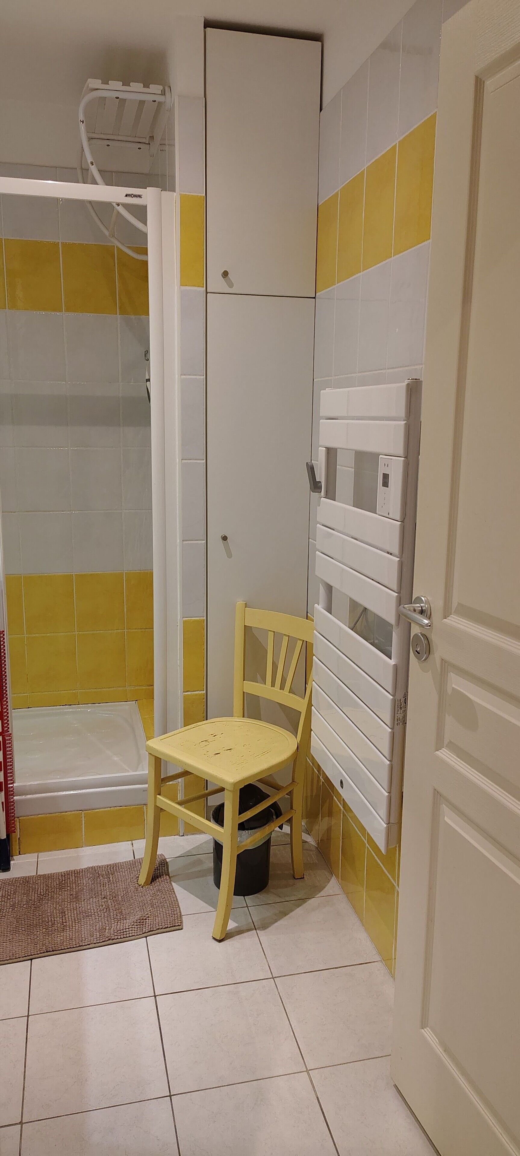 Un bagno con doccia, un water e una sedia.