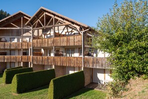 A multi-story wooden building with balconies and a well-maintained garden.