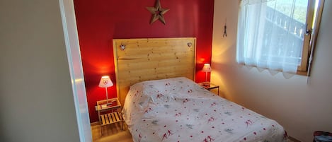 Un dormitorio con cabecera de madera, dos lámparas de noche, una cama con colcha estampada y una decoración de estrella en la pared.