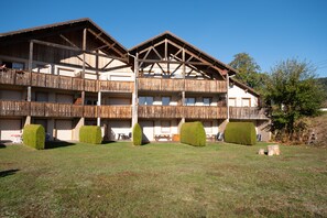A multi-story building with balconies, a flat roof, and a grassy courtyard.