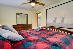 Ein Schlafzimmer mit einem Bett, einem Deckenventilator, einem Schminktisch, einem Spiegel und einem großen gerahmten Bild von Hirschen an der Wand.