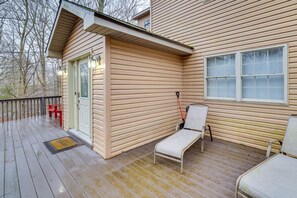 Eine Holzterrasse mit überdachtem Bereich, einer roten Bank und einem weißen Stuhl.