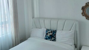 Ein Schlafzimmer mit einem Bett, einem Nachttisch, einem Spiegel und einer Pendelleuchte.