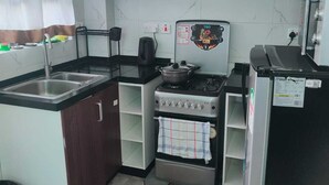 Eine kleine Küche mit Gaskochfeld, Backofen, Spüle und Kühlschrank.