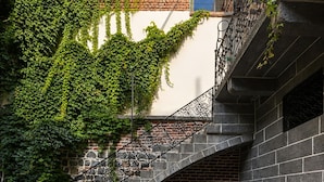 A courtyard with a stone fountain, outdoor seating, and a brick staircase. - Taş Avlu Konaklama (Diyarbakir)