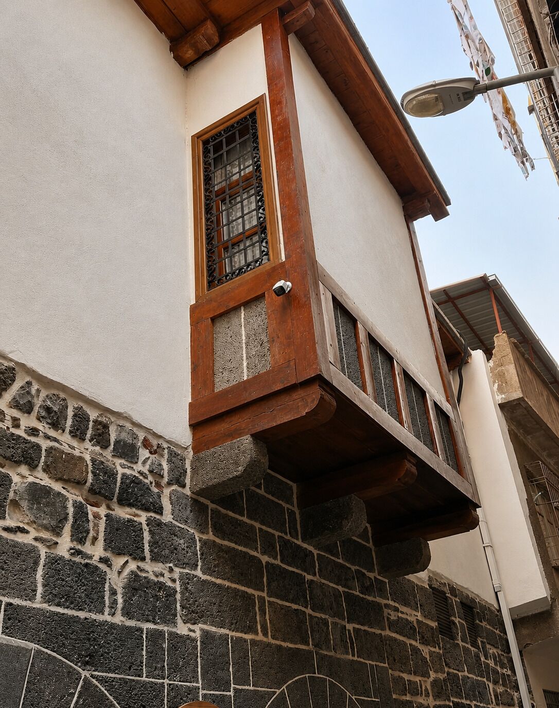 Esquina de un edificio con base de piedra y sección superior blanca.