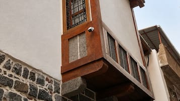 Esquina de un edificio con base de piedra y sección superior blanca.