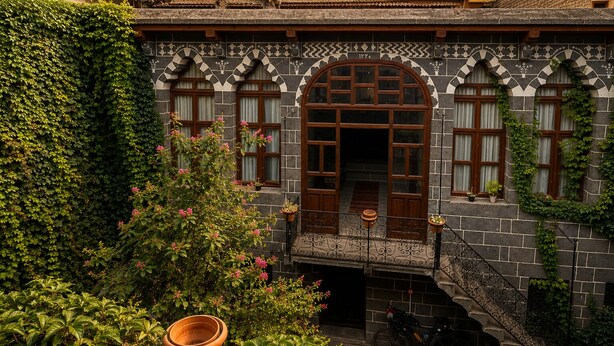 A building with a stone facade, arched windows, and a balcony with a wrought iron railing. - Taş Avlu Konaklama (Diyarbakir)