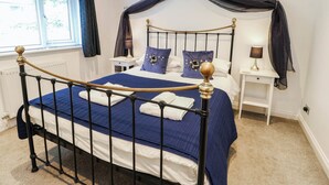 Um quarto com uma cama de dossel, duas mesas de cabeceira e uma janela com cortinas.