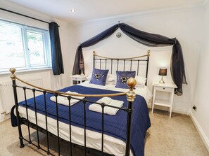 Ein Schlafzimmer mit einem Himmelbett, zwei Nachttischen und einem Fenster mit Vorhängen.