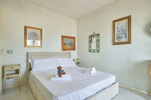 A hotel room with a bed, a bedside table, a nightstand, and a wall with three framed pictures. - Lo Scirocco (Andora)