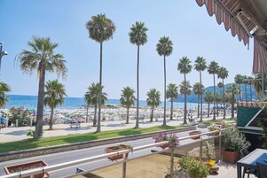 Vista de la playa con palmeras, un paseo marítimo y el mar al fondo.