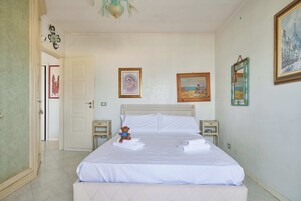Una habitación de hotel con una cama, un osito de peluche y obras de arte en las paredes.