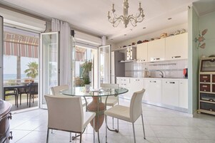Una cocina moderna con armarios blancos, una mesa de comedor de vidrio y vistas al exterior.