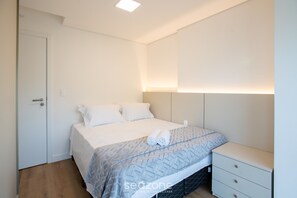 Una camera da letto ordinata con un letto, un comodino e una porta.