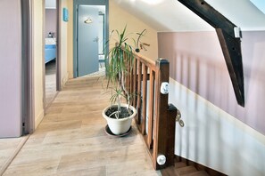 A wooden staircase with a potted plant, leading to a room with a bed and a bathroom.