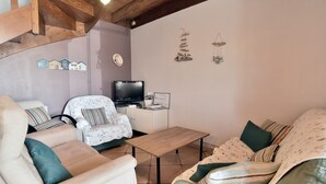 Una sala de estar acogedora con un sofá, un sillón y un televisor.