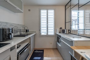 Una cocina compacta con horno empotrado, cafetera y hervidor sobre la encimera.