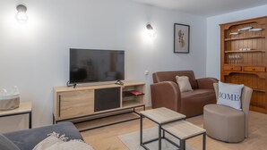 Ett modernt vardagsrum med en platt-TV, en soffa i läder, ett träskåp och ett litet bord.