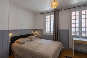 Un dormitorio con cama, lámparas de noche, un escritorio y una ventana.