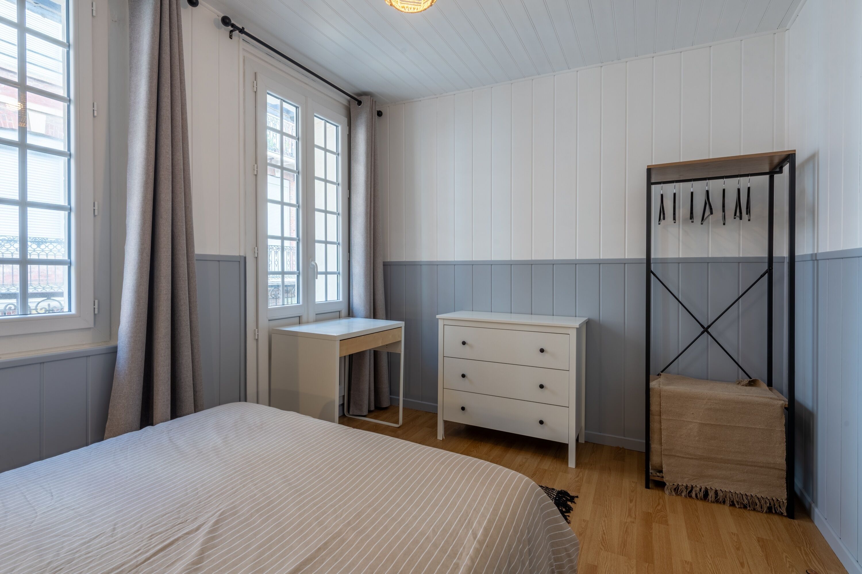 A bedroom with a bed, a desk, a dresser, and a wardrobe.