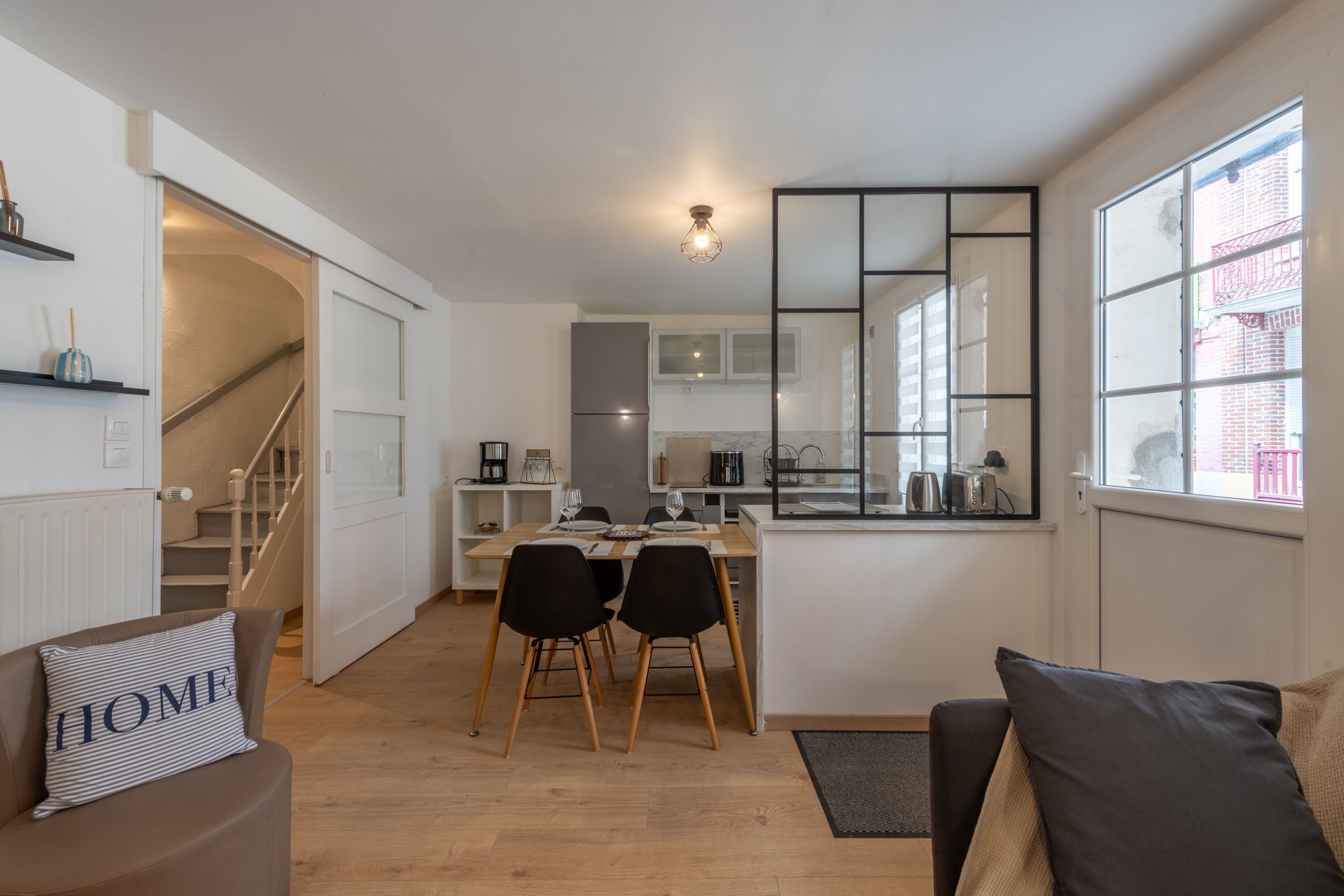 A modern apartment with a dining area, kitchen, and a living space with a sofa and a coffee table.