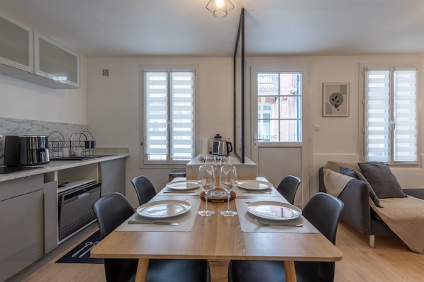 Una cocina moderna con comedor, que incluye una mesa preparada para cuatro personas, con platos, vasos y cubiertos.