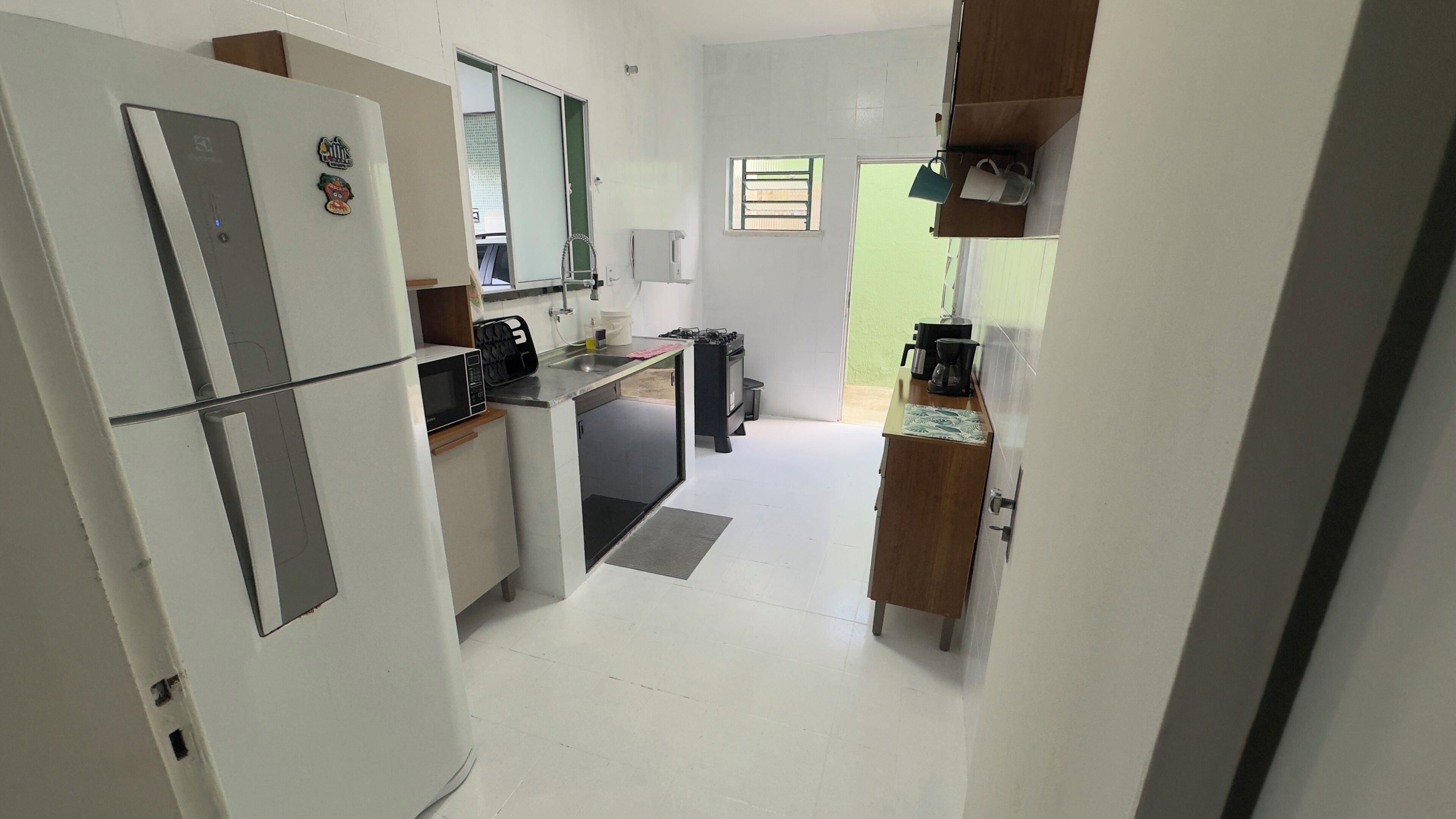 A compact kitchen with a refrigerator, microwave, stove, and sink.