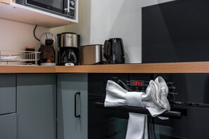A kitchen with a microwave, coffee maker, and oven. - Le Discret de Charles - Calme & Confort (Nancy)