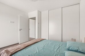 Ein Schlafzimmer mit einem Bett, einem Kleiderschrank und einer Tür zu einem anderen Raum.