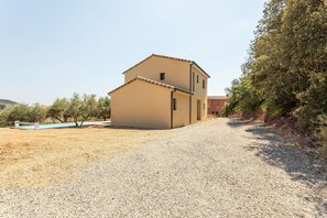 Un bâtiment à deux étages avec une allée de gravier menant à l’entrée.